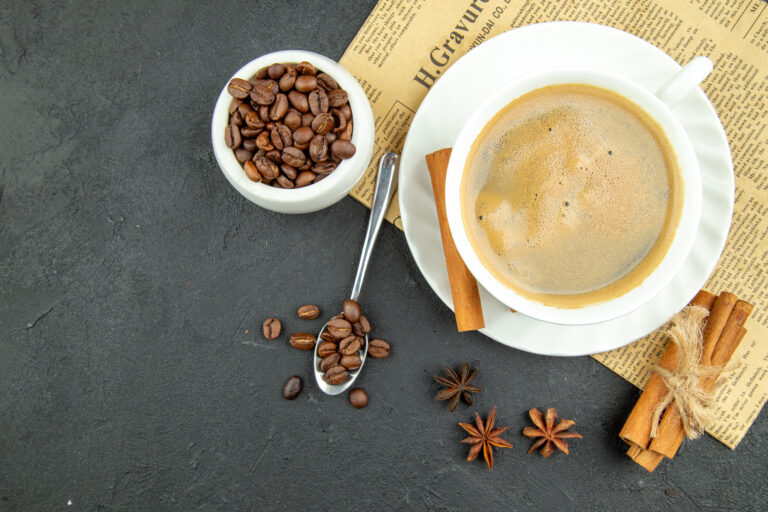 Above view of a cup of delicious coffee and cinnamon limes on dark backgorund